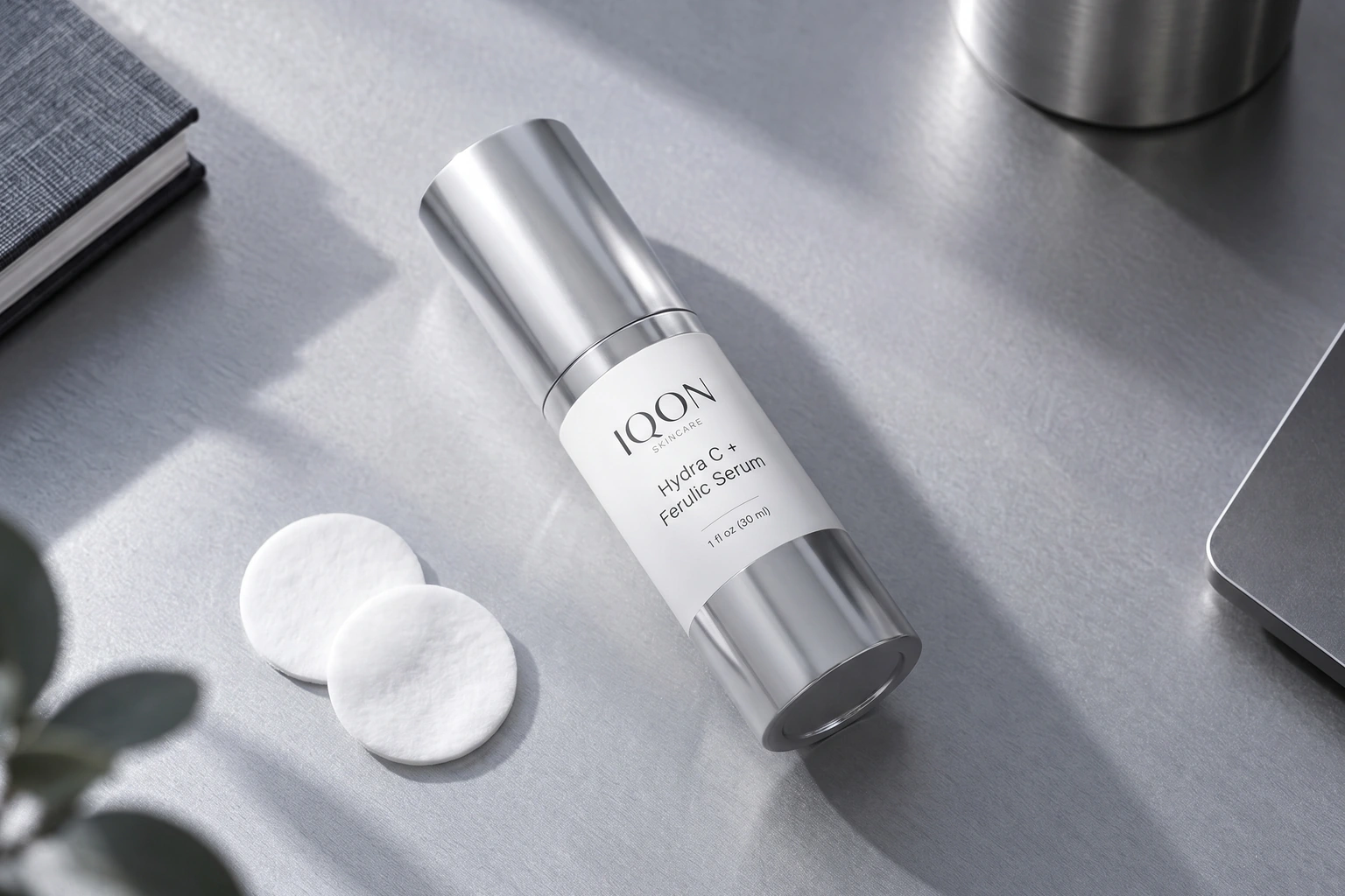 IQON Hydra C + Ferulic Serum and cosmetic pads on a silver desk