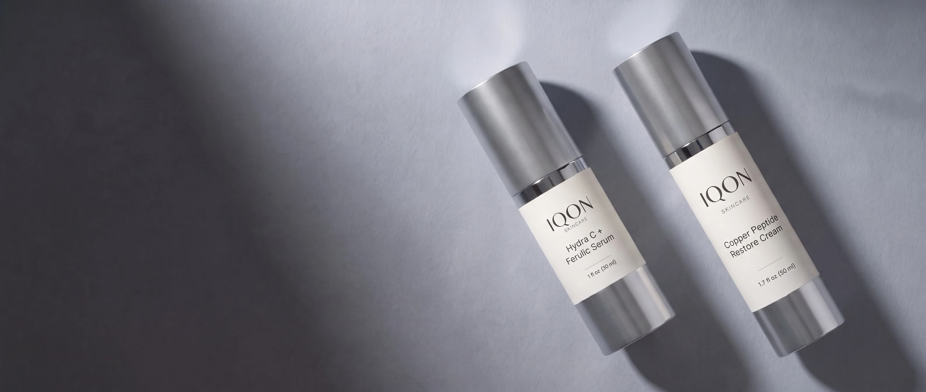 IQON Hydra C + Ferulic Serum and Copper Peptide Restore Cream on a cool blue-gray surface